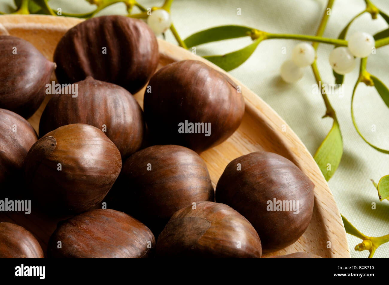 Sweet Chestnuts with Christmas Mistletoe in the background. Stock Photo