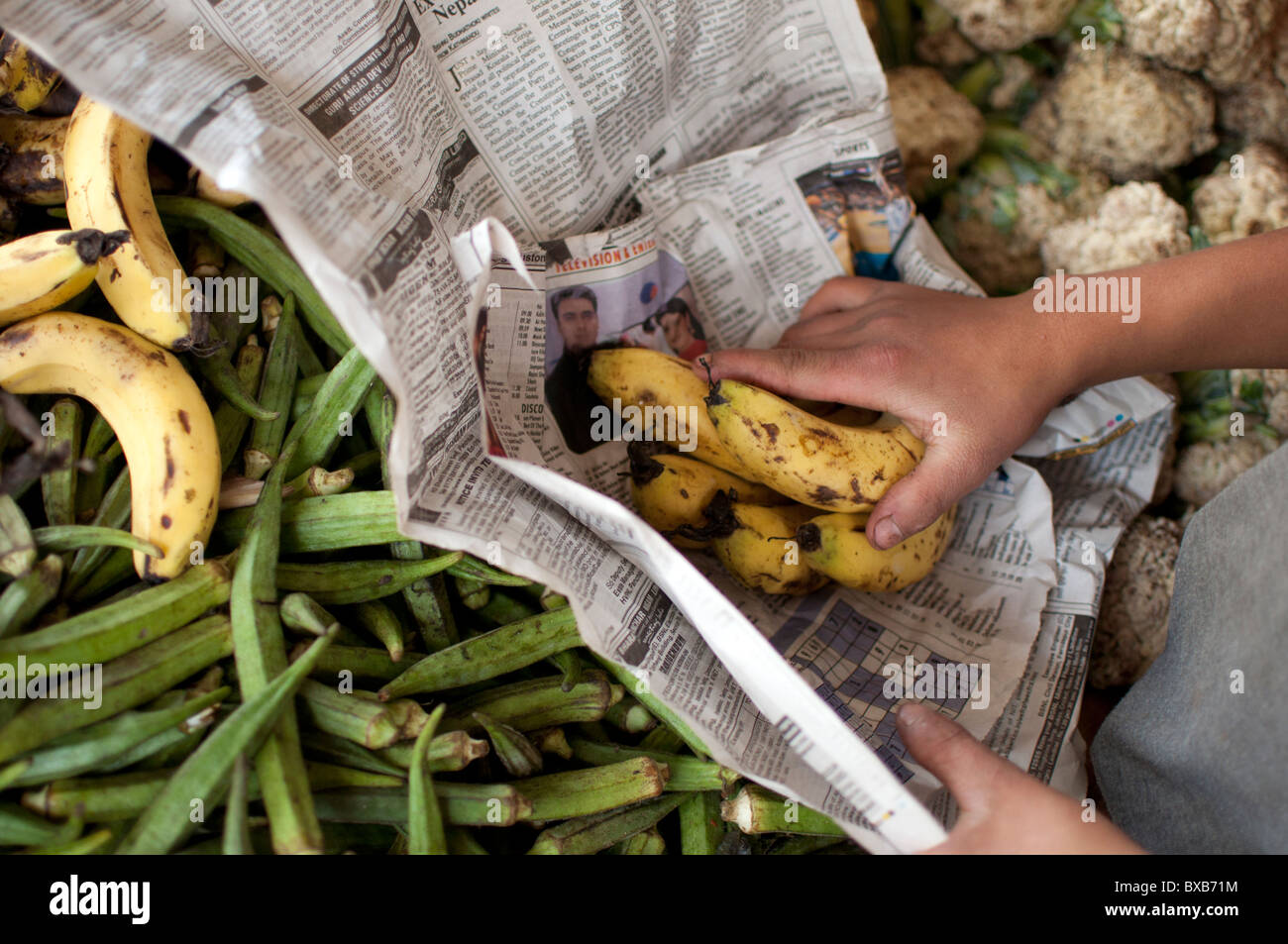 A young boy packs Bananas into newspaper, India. Stock Photo