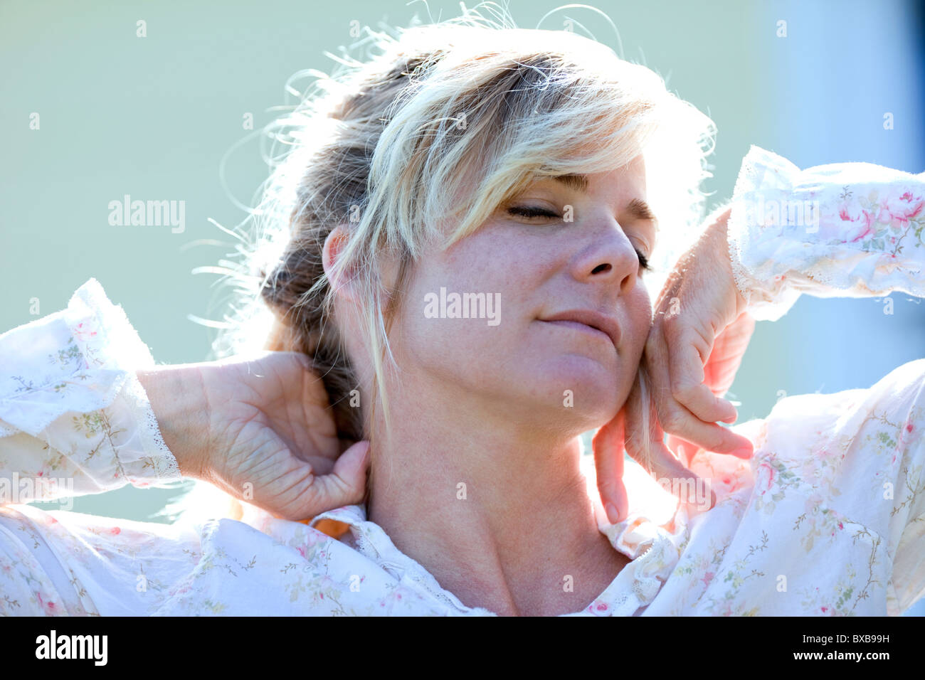 Woman in nightgown stretching with eyes closed Stock Photo