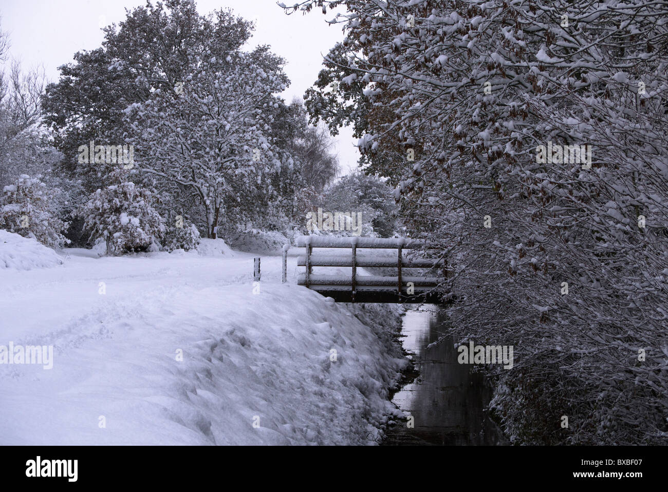 Snow covered back lane with foot bridge over storm drain. Stock Photo