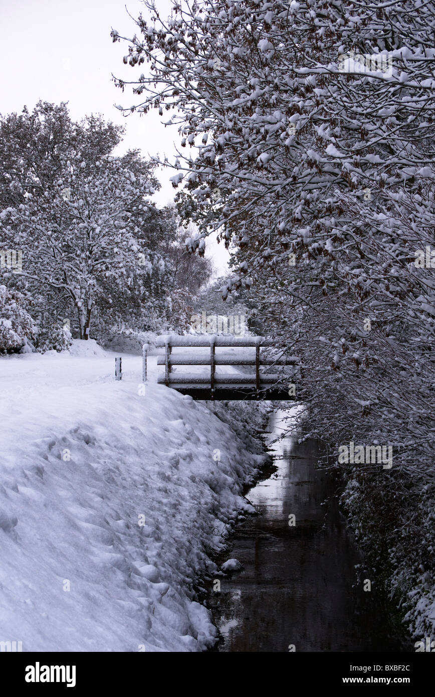 Snow covered back lane with foot bridge over storm drain. Stock Photo