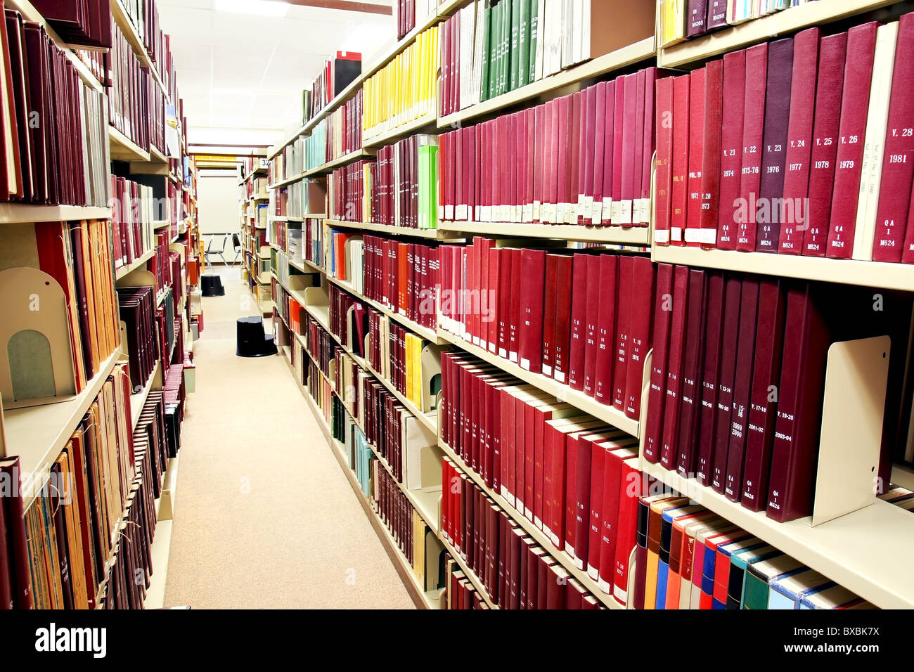 Long and narrow row of mainly red books at the university library. Stock Photo