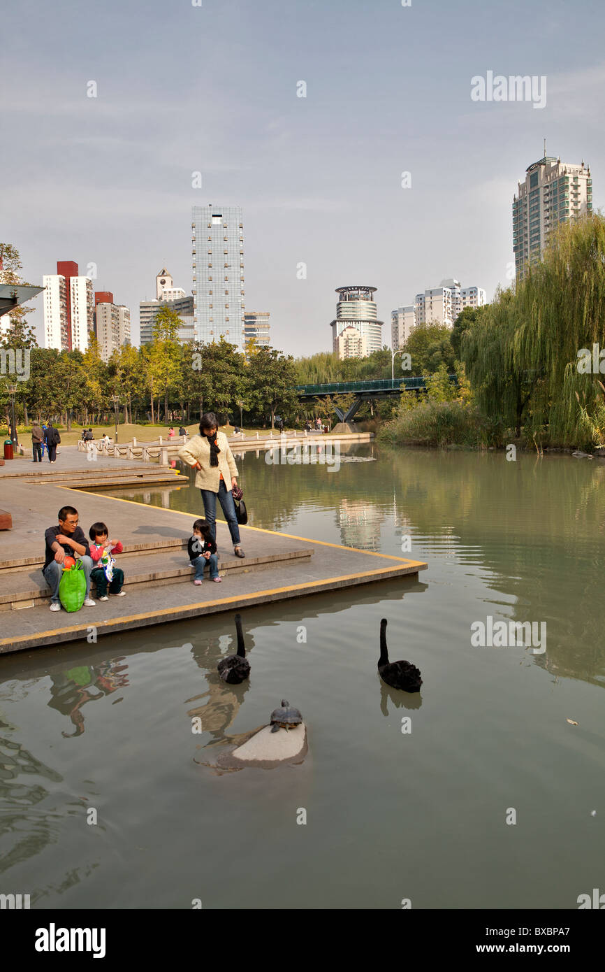 Family looking at swans in Xujiahui Park, Shanghai, China Stock Photo