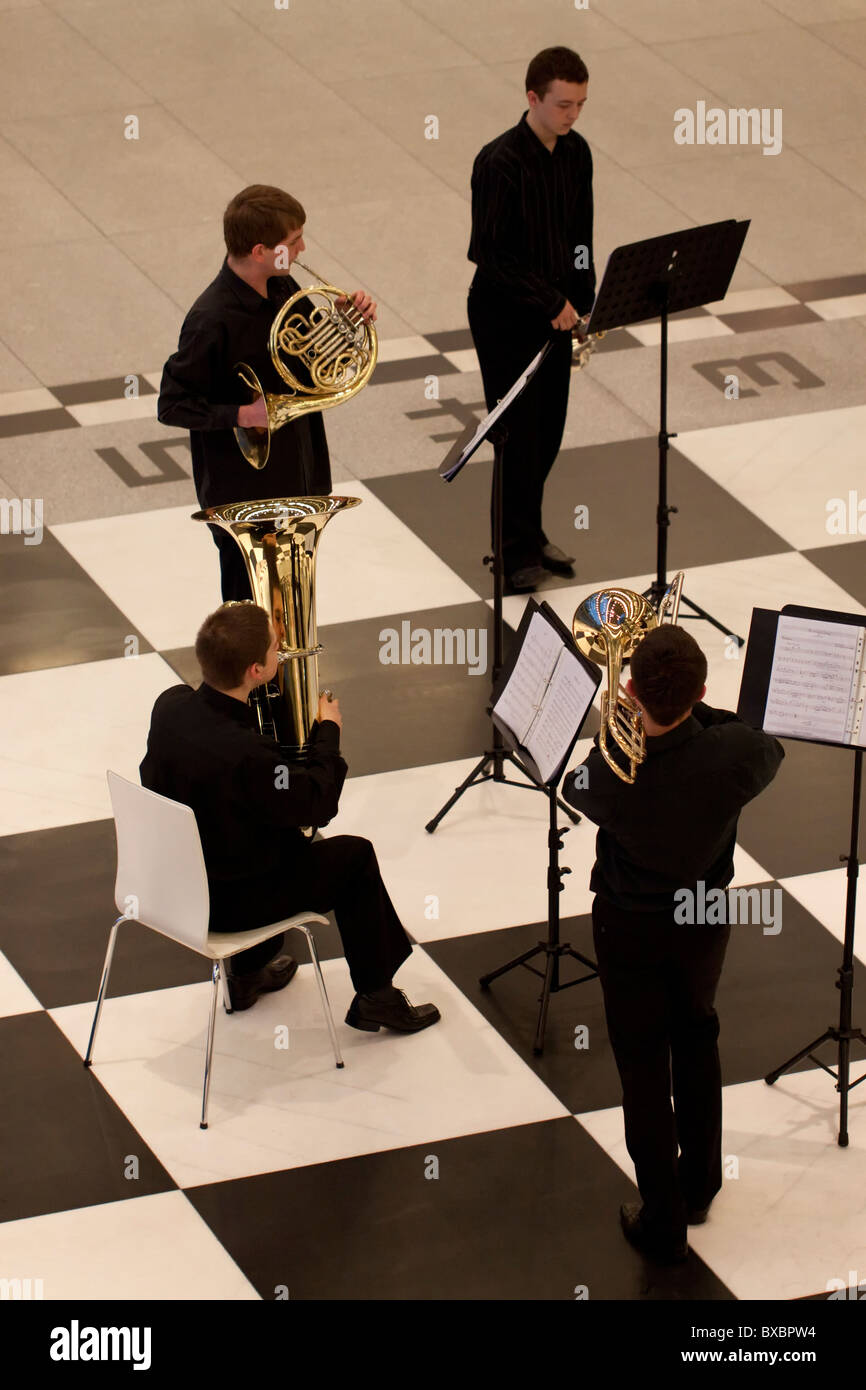 A brass quartet giving a concert on a large floor chessboard in Stary Browar, Poznan, Poland Stock Photo