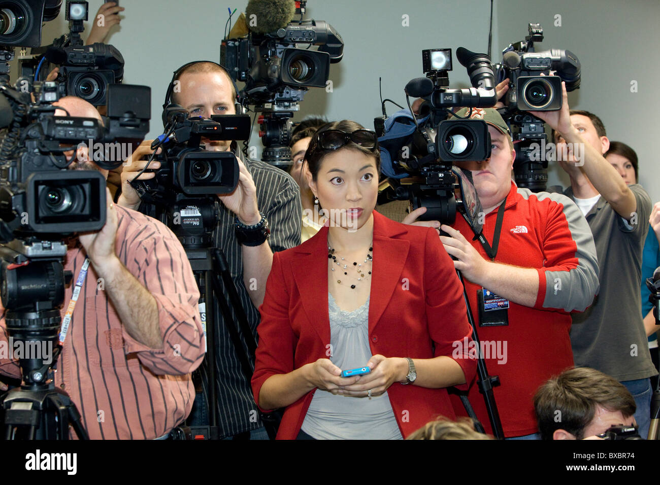 Asian-American female news reporter tweets breaking news update on her cellphone during press conference in Austin, Texas Stock Photo