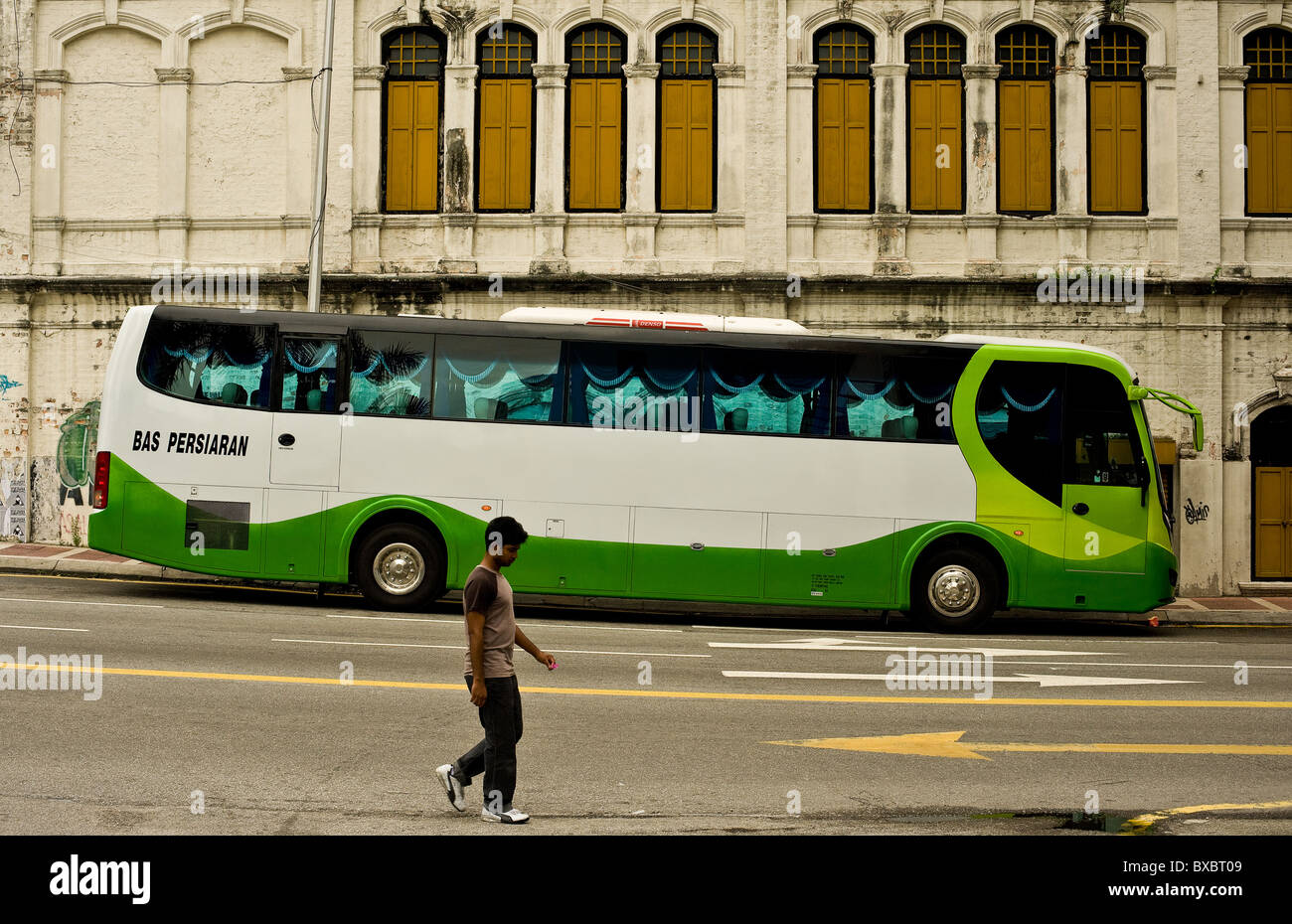 A man walking past a bus coach in a street in Kuala Lumpur.  Photo by Gordon Scammell Stock Photo