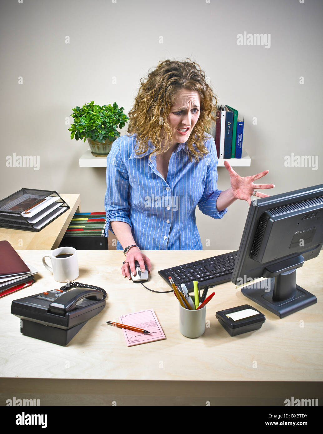Female secretary, executive, office worker at computer desk. stressful situation. Unorganized. Stock Photo