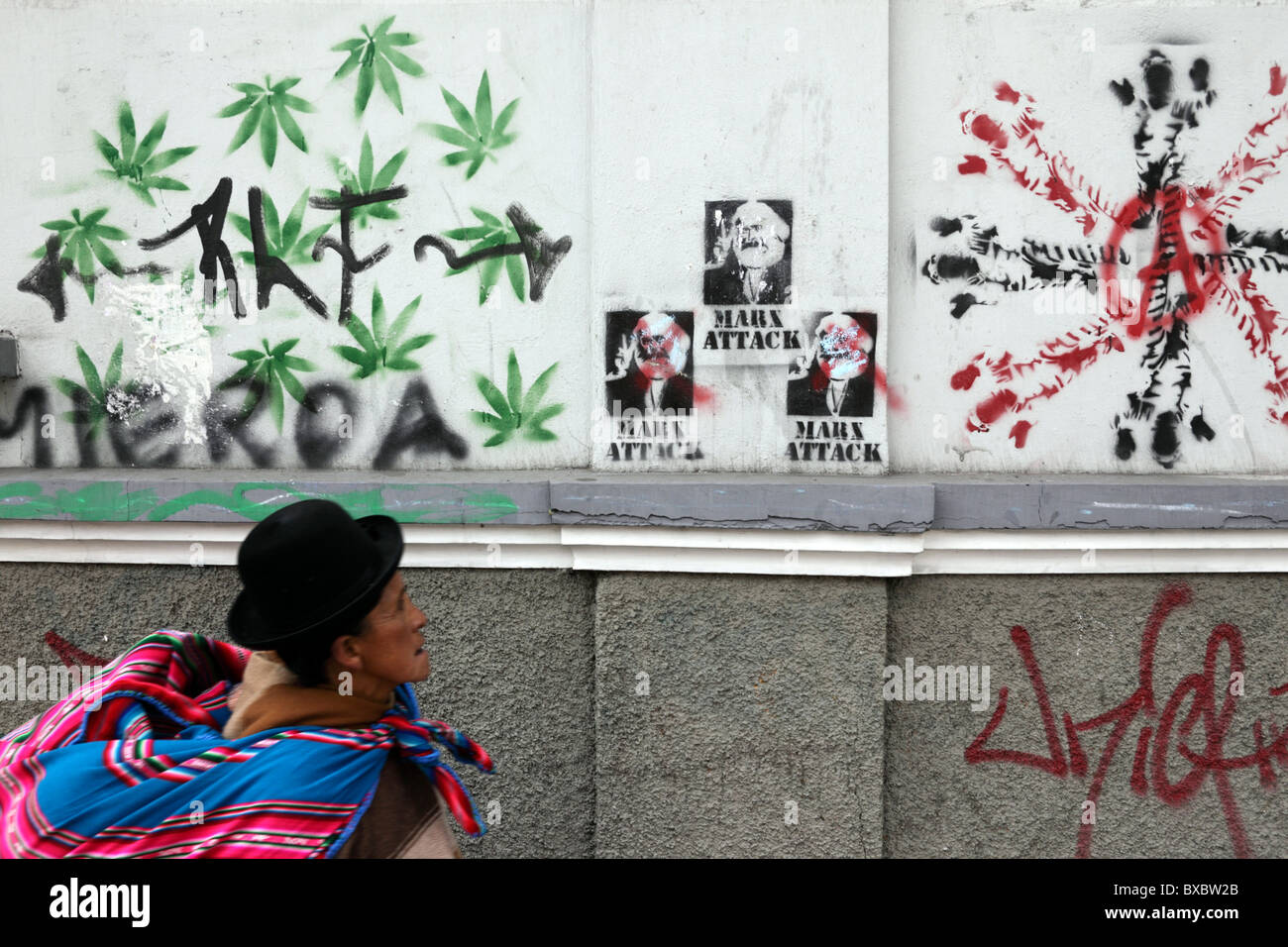Aymara lady or cholita passing wall with spray painted marijuana leaves and Karl Marx graffiti, La Paz, Bolivia Stock Photo