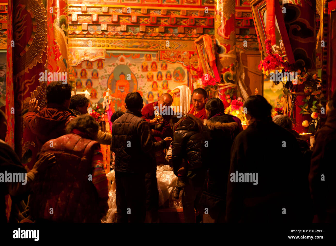 A Tibetan monk blesses lamaist adherents during a ceremony in Tagong Temple, Sichuan province, China Stock Photo