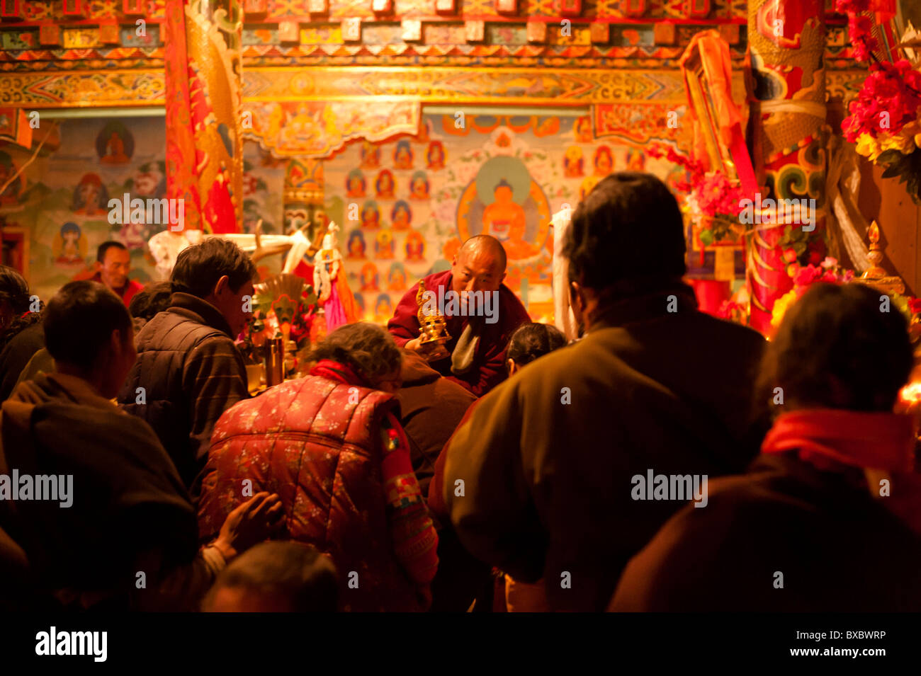 A Tibetan monk blesses lamaist adherents during a ceremony in Tagong Temple, Sichuan province, China. Stock Photo