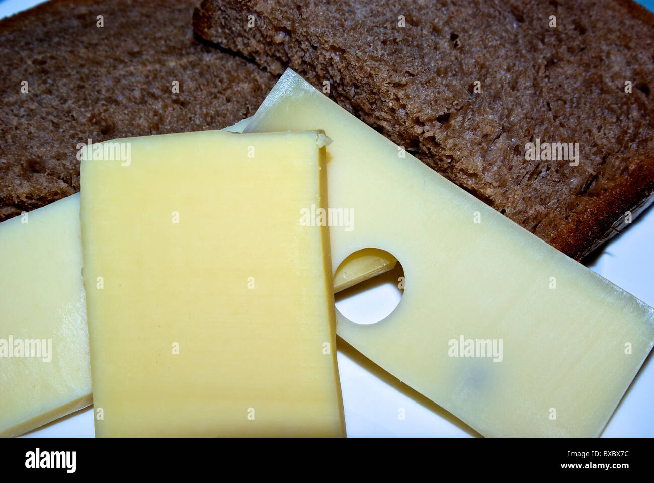 Cheese plate with three hard Swiss cheeses sliced dark rye bread Stock Photo
