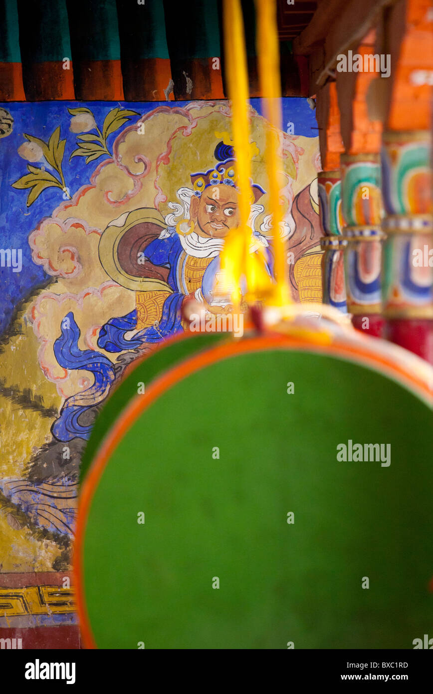 Prayer drums hanging in front of a buddhist wall painting at the