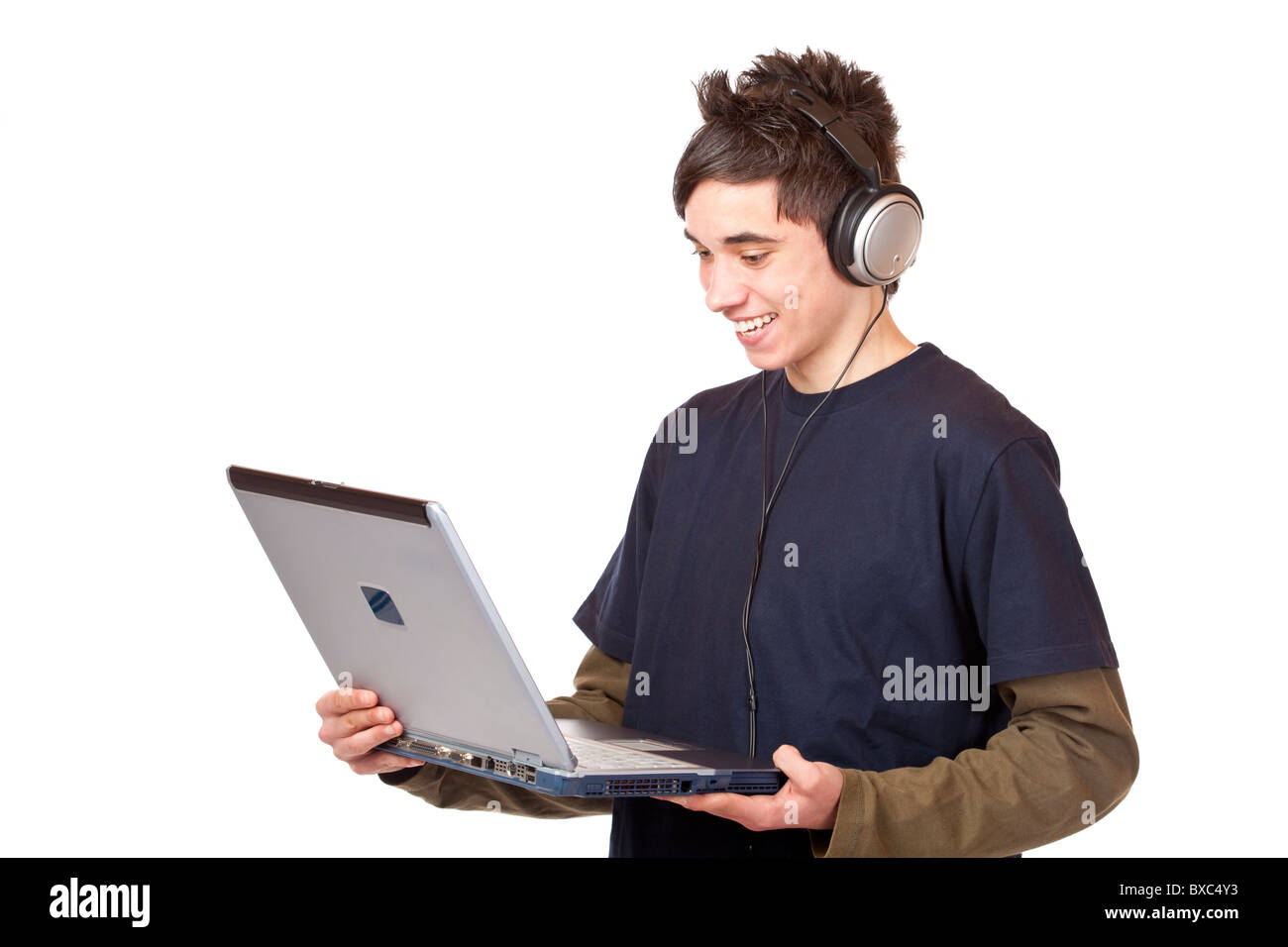 Teenager with headset makes internet mp3 music download at computer. Isolated on white background. Stock Photo