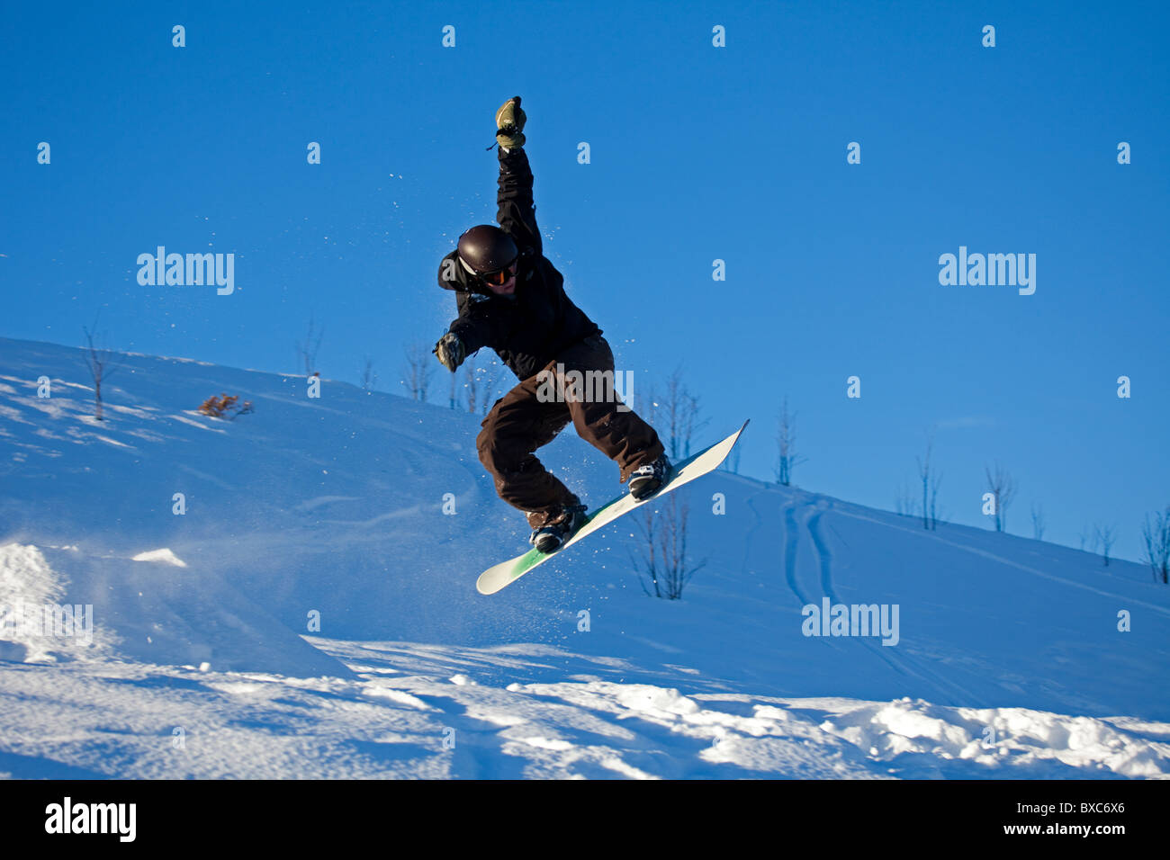 Snowboarder jumping in air from ramp surrounded by snow, Arthurs Seat