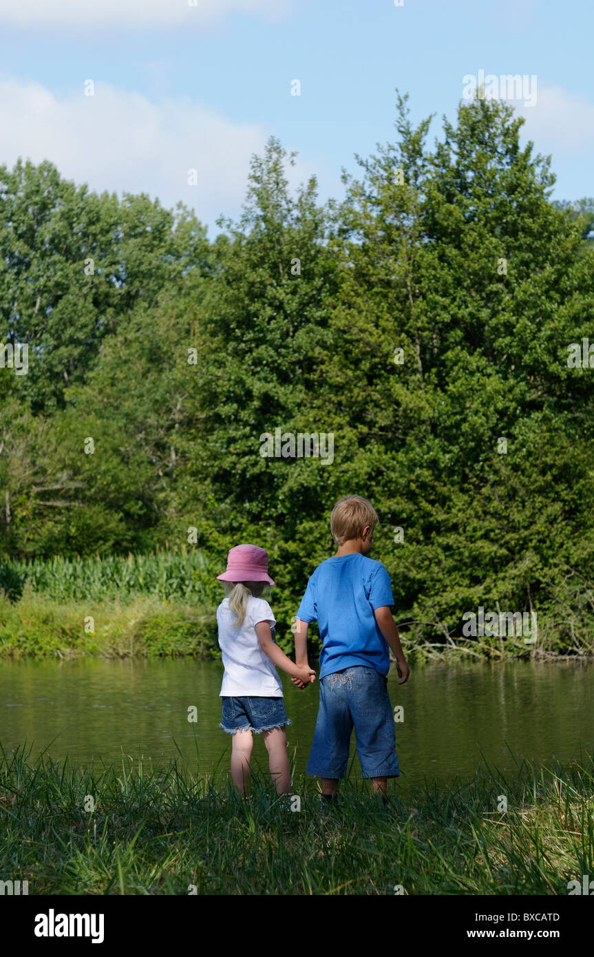 Stock photo of a brother and sister standing next to a river. Stock Photo