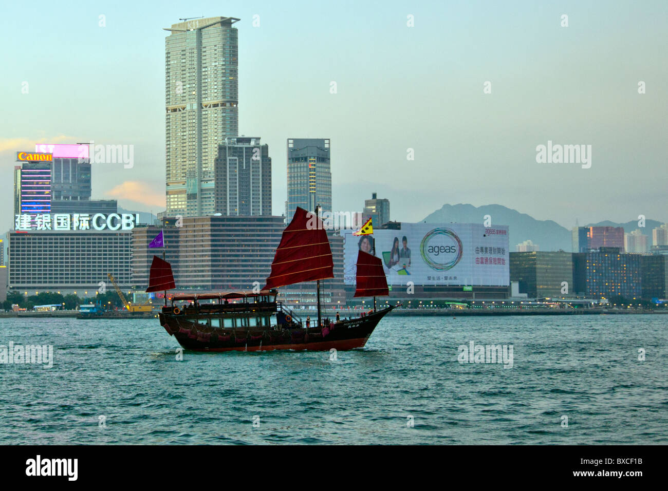Hong Kong Junk Trips on Victoria Harbour, Harbor, with Kowloon in the background red bat wing sails iconic sight Stock Photo