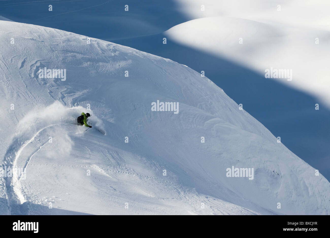 Telemark skier making a turn in powder snow on rugged terrain in
