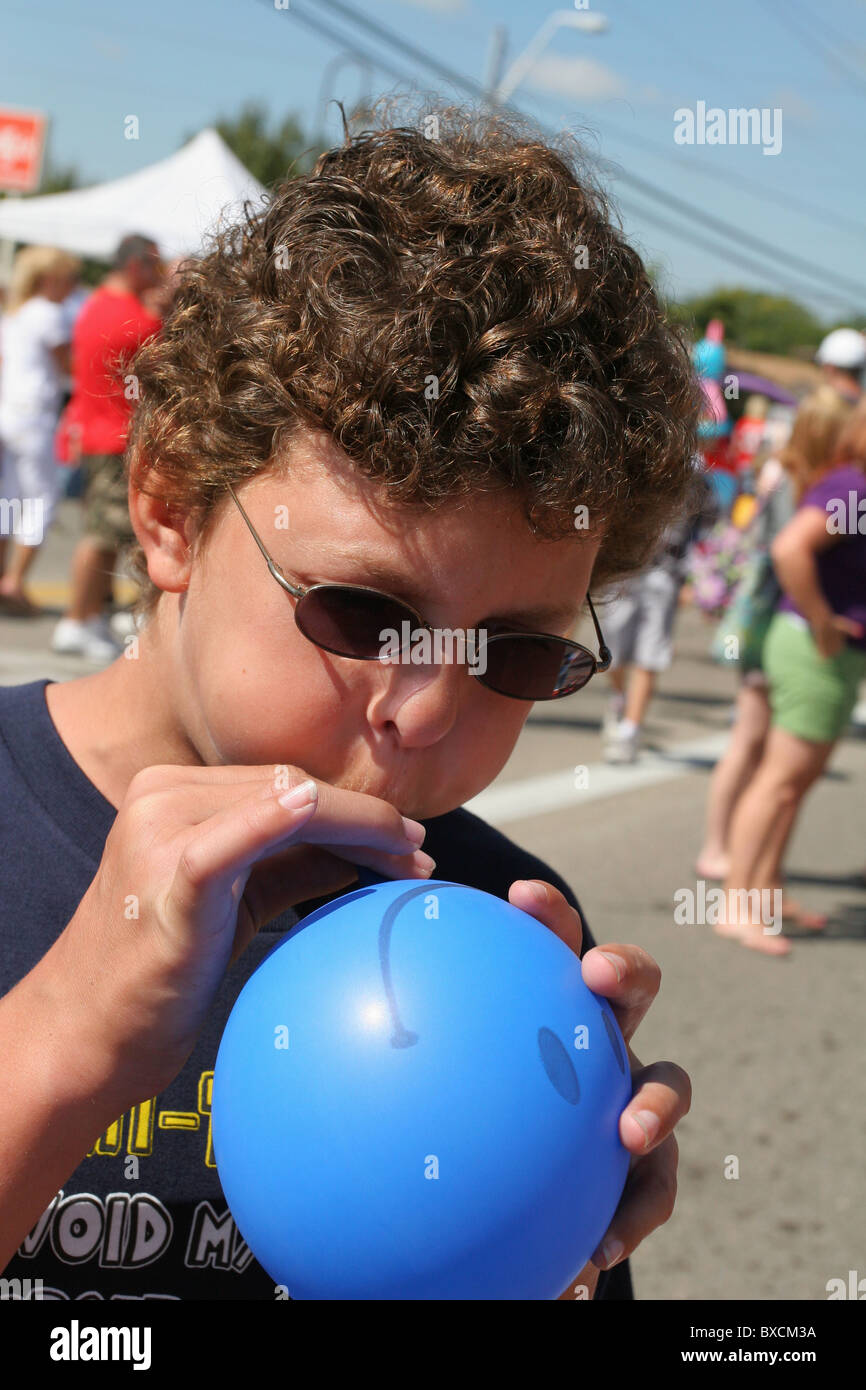 Preteen boy blowing up a smiley face balloon. Beavercreek Popcorn