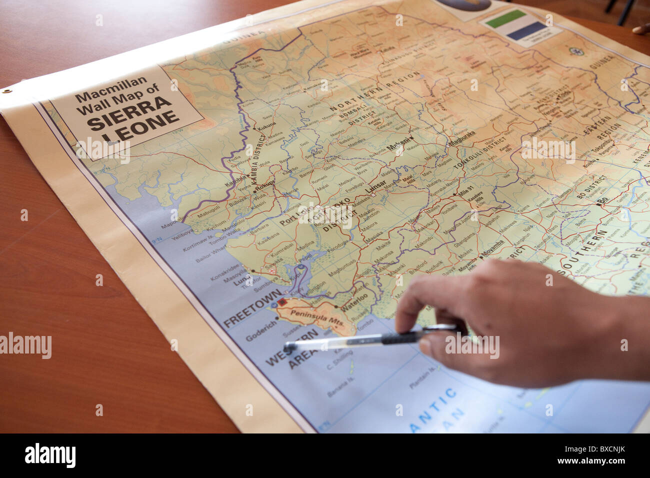 A man points to points on a map of Sierra Leone, West Africa. Stock Photo