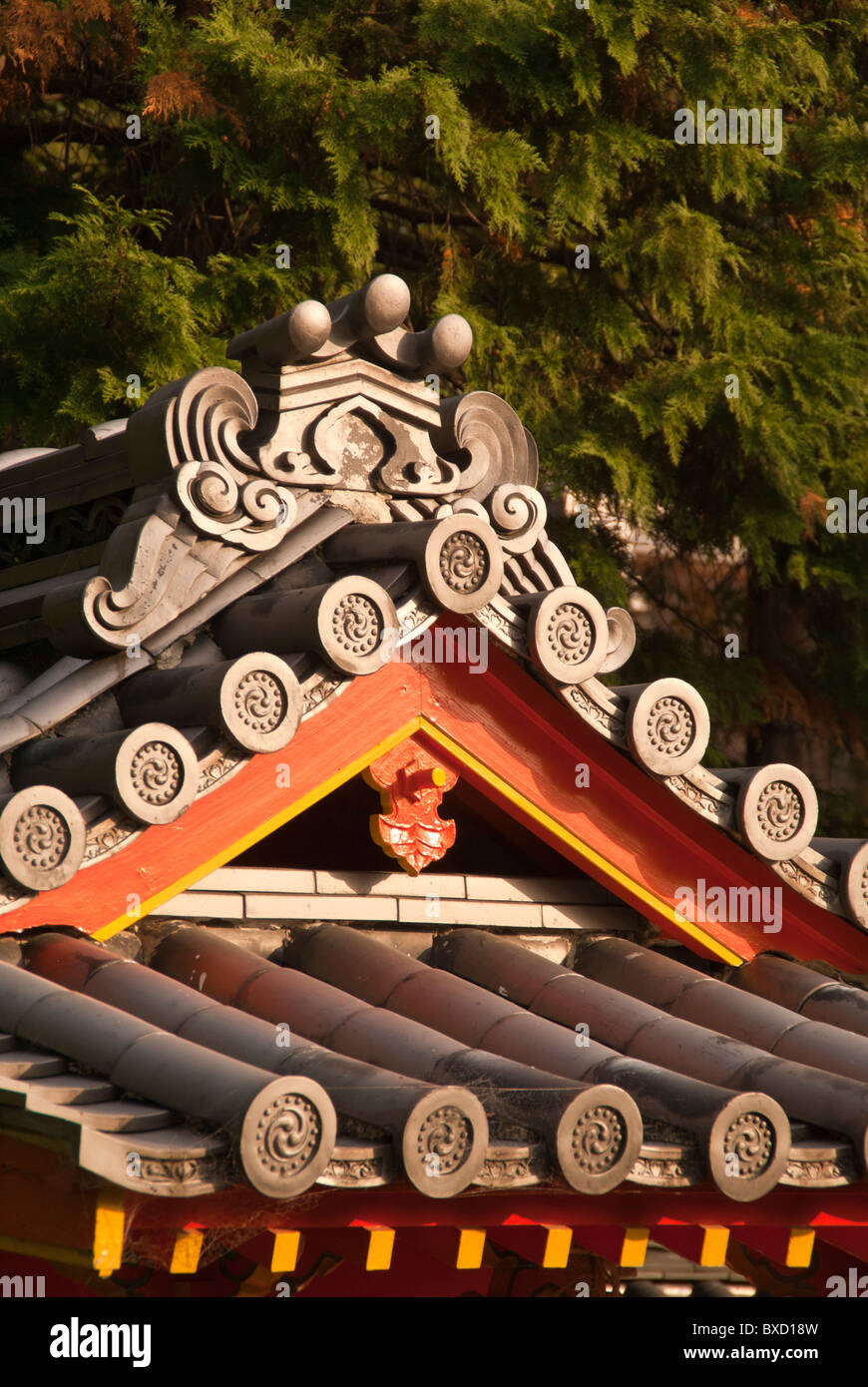 A shot of a tiled Japanese temple roof against a background of trees Stock Photo