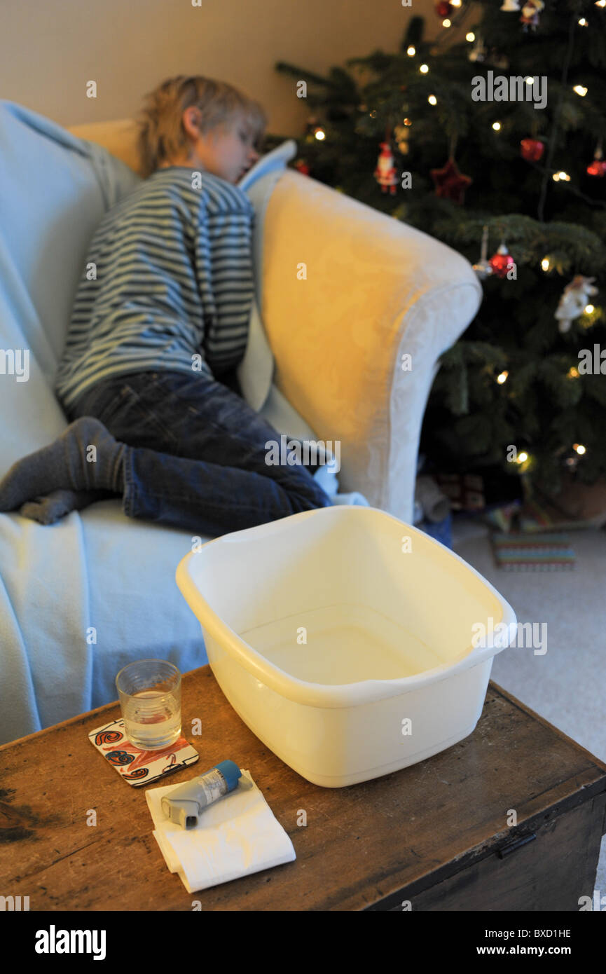 An ill child suffering from the winter vomiting bug asleep on a sofa by