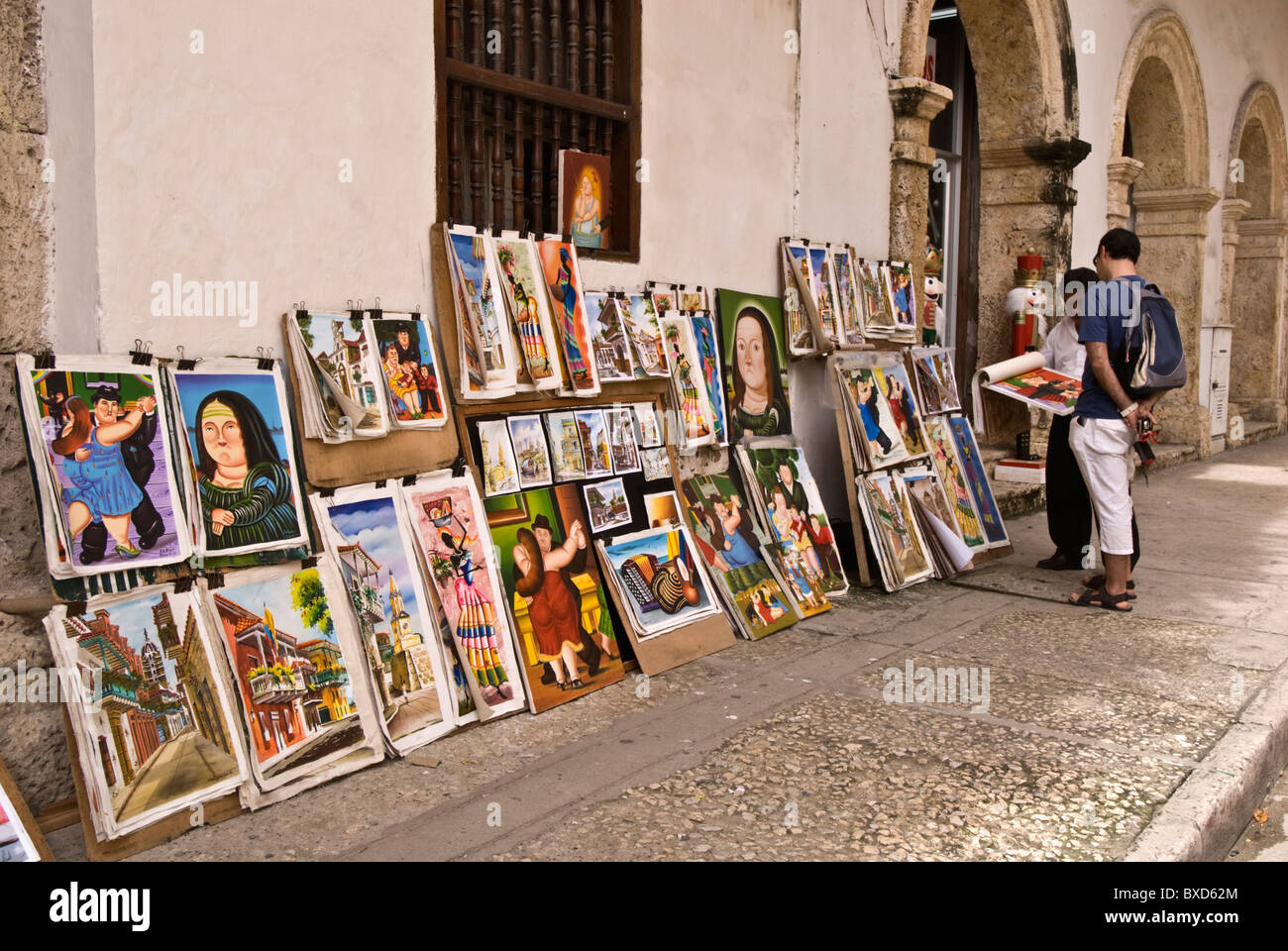 A street vendor shows his collection of local art to a tourist, Old Town, Cartagena de Indias, Colombia Stock Photo