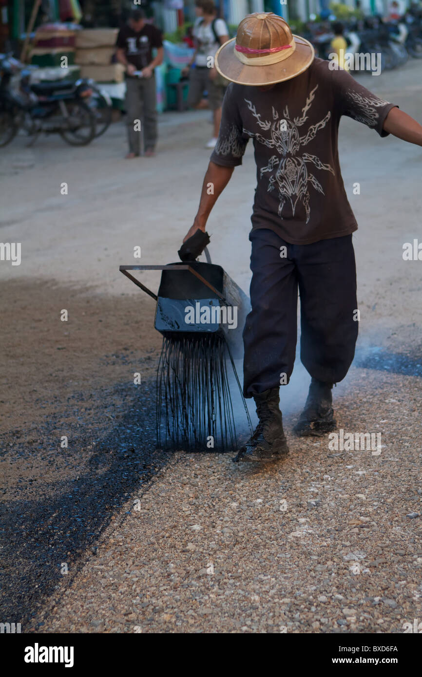 burmese man pouring tar on the road Stock Photo