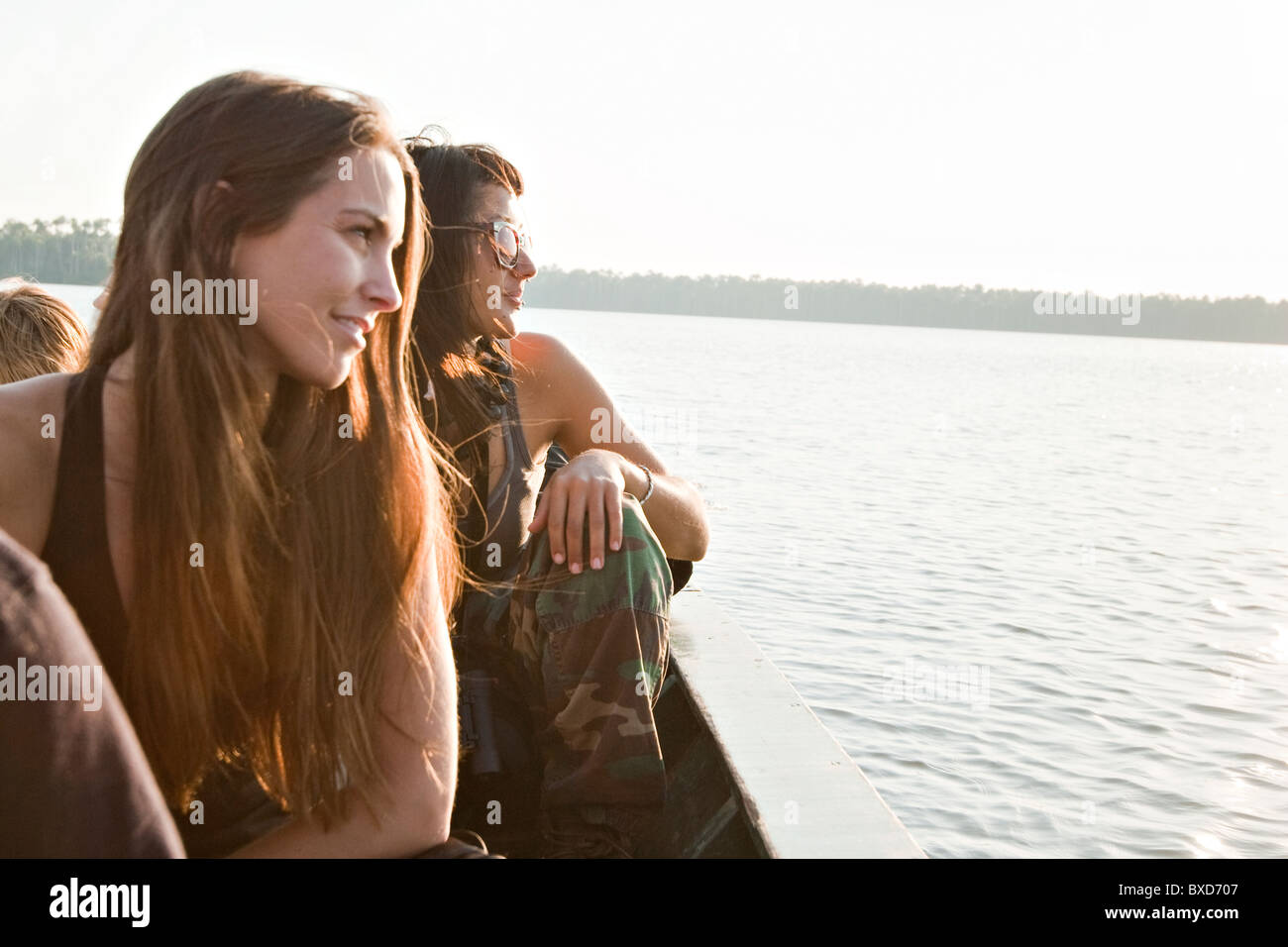 Two young women look into the sunset over Lake Sandoval, in the amazon rainforest. Stock Photo