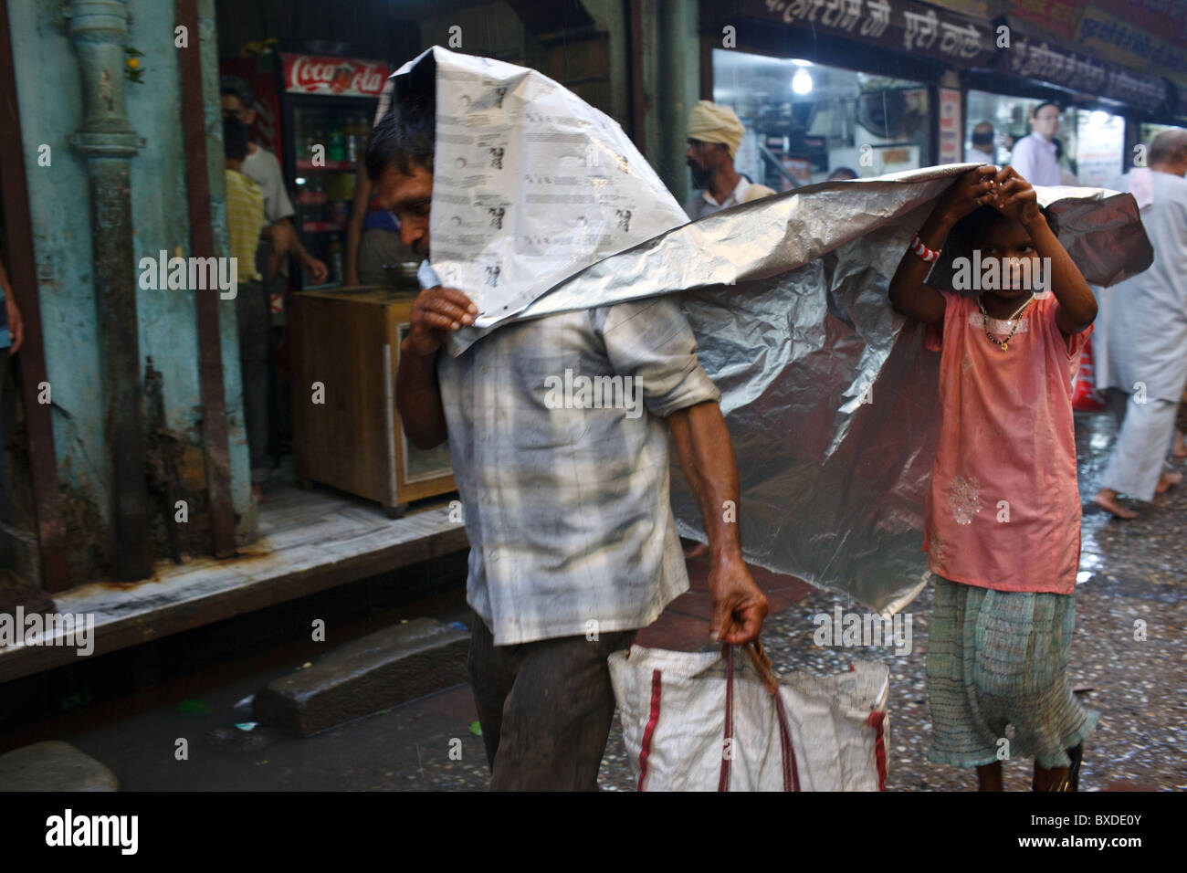 A man covers himself under a plastic sheet from the rain in Haridwar