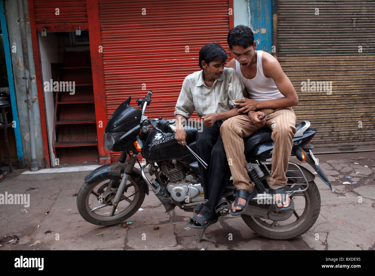 Two young men on a bike listen to music from a mobile phone in Old Delhi, capital of India. Stock Photo
