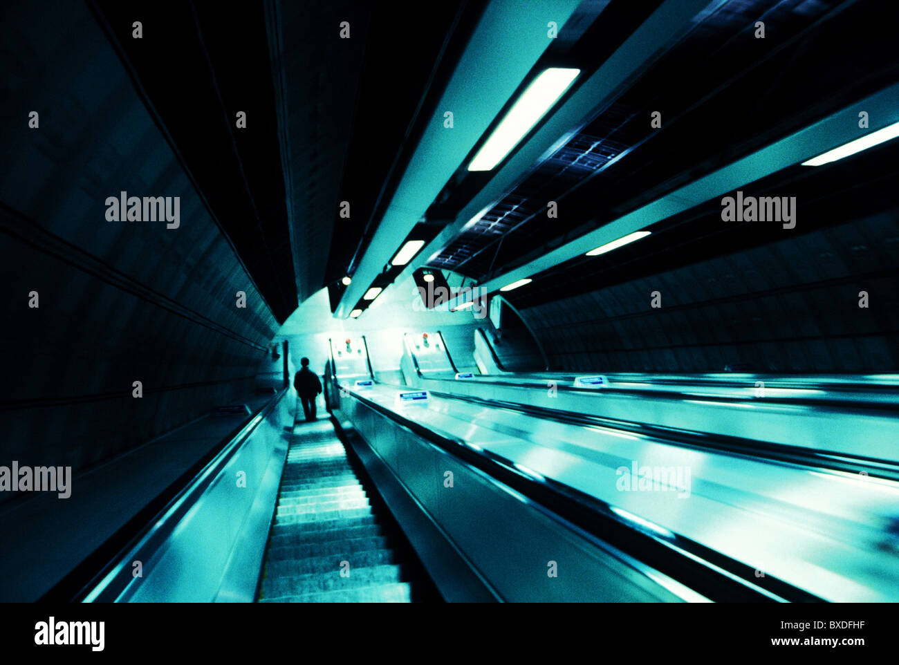 One person at the bottom of the escalator in Westminster Station on the London Underground transport network. Stock Photo