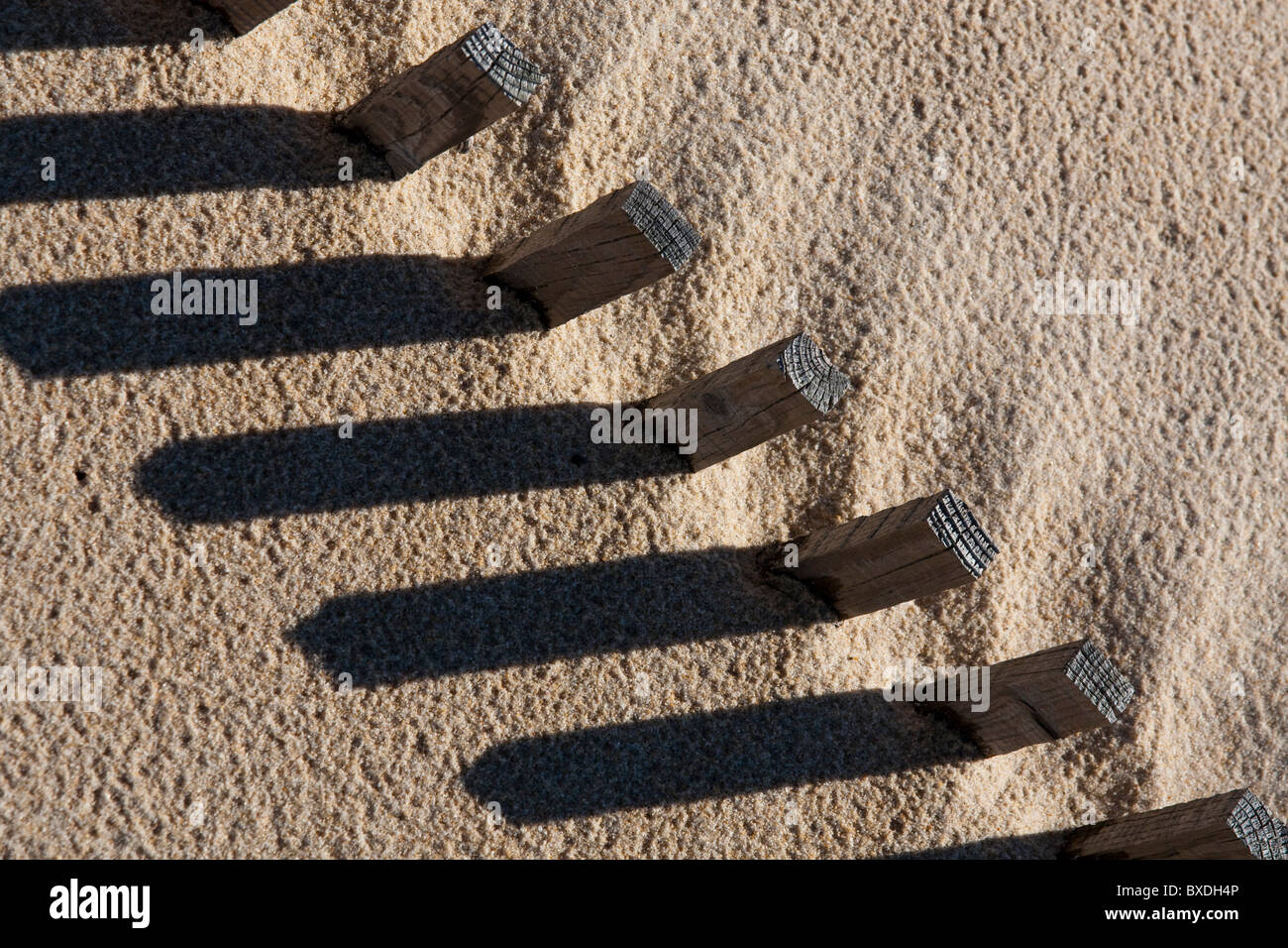 View of a section of a fence buried on the sand making a shadow. Stock Photo