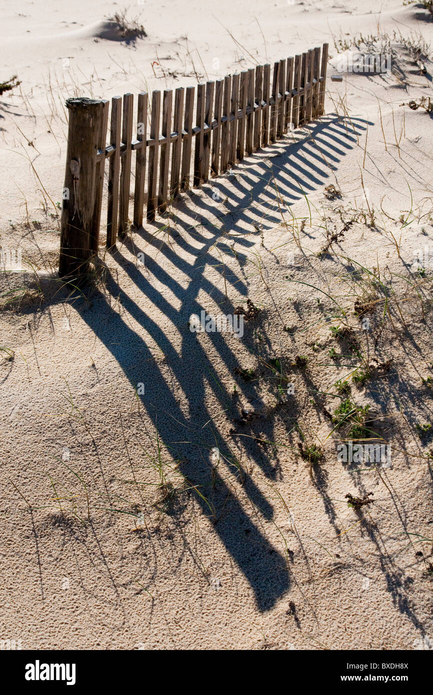 View of a section of a fence buried on the dune sand on the beach. Stock Photo