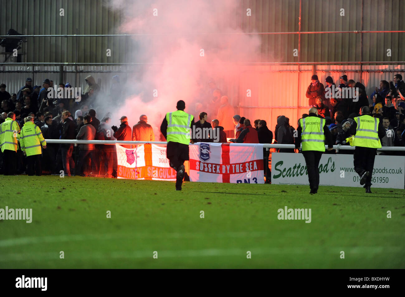 Woking football club, stewards rush over to the away fans after one of them lets off a flare after the match finished Stock Photo