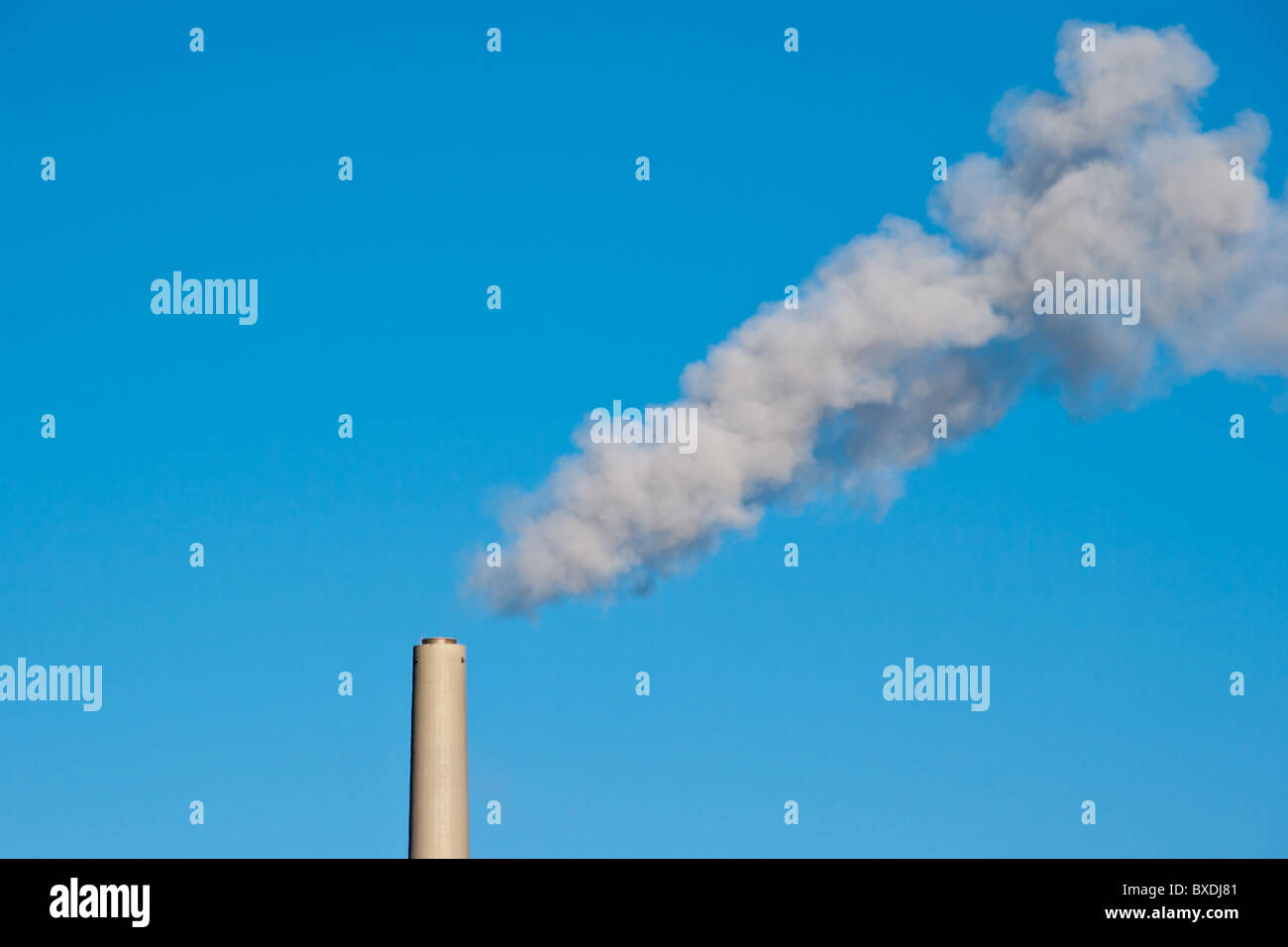 Smoke from coal power plant chimney against blue sky. Symbol of global warming and smoke pollution. Stock Photo