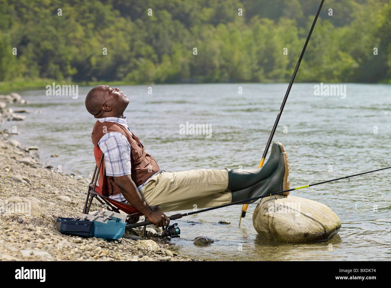 Black man with feet up fishing in stream Stock Photo - Alamy