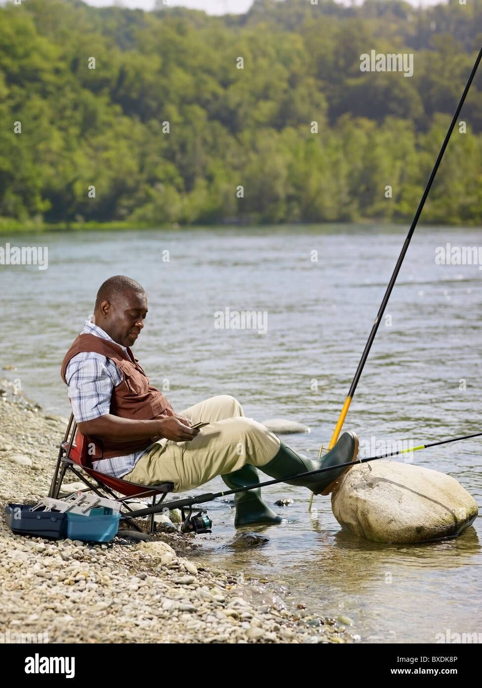 Black man with cell phone fishing in stream Stock Photo - Alamy