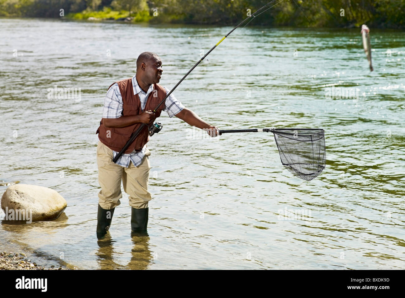 Black man with net catching fish in stream Stock Photo - Alamy