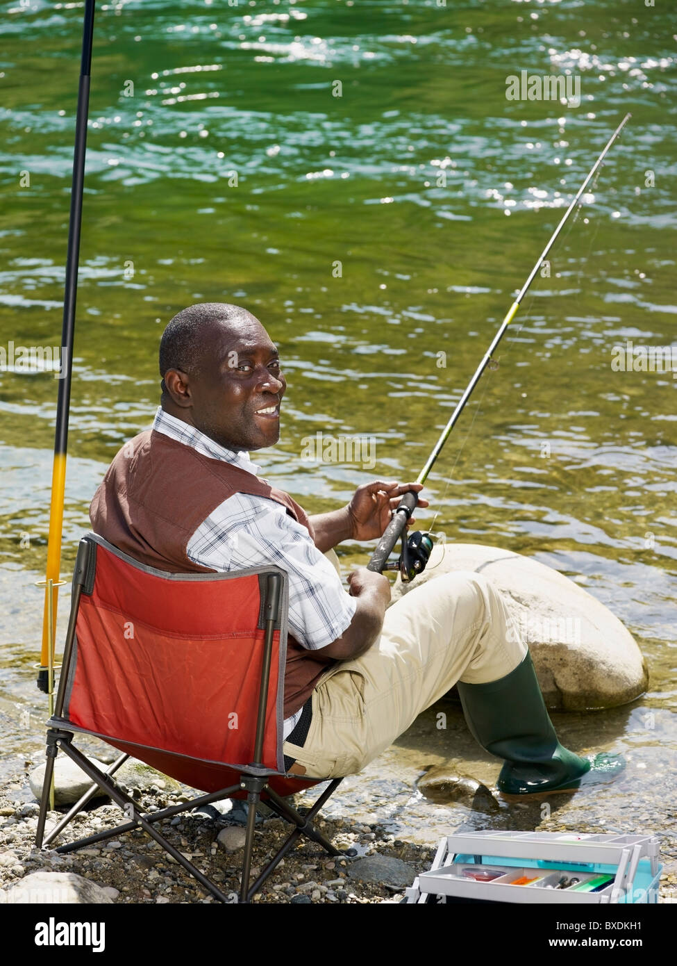 Smiling Black man fishing in stream Stock Photo - Alamy