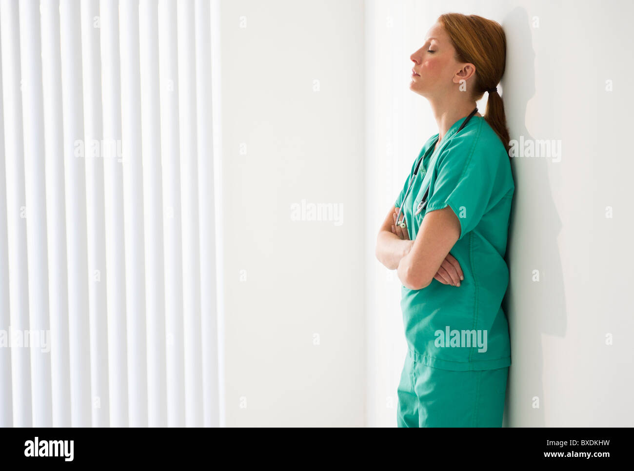 Tired doctor leaning against wall Stock Photo