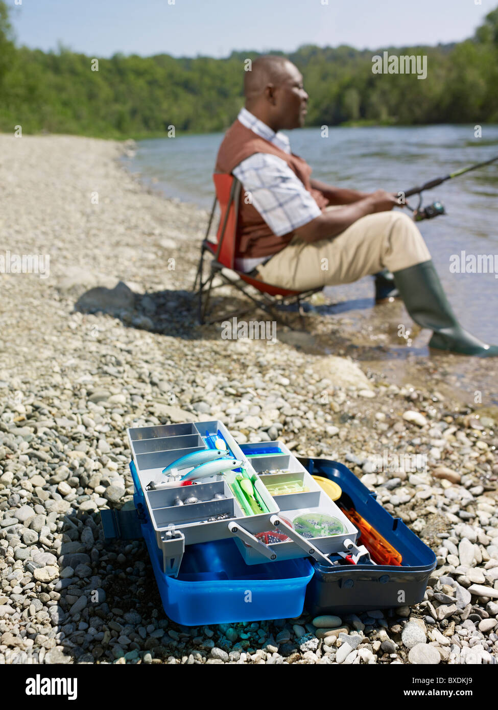 Black man with tackle box fishing in stream Stock Photo - Alamy
