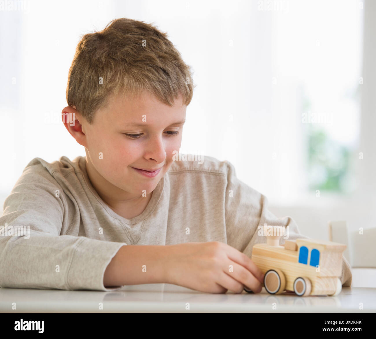 Young boy looking at wooden train Stock Photo