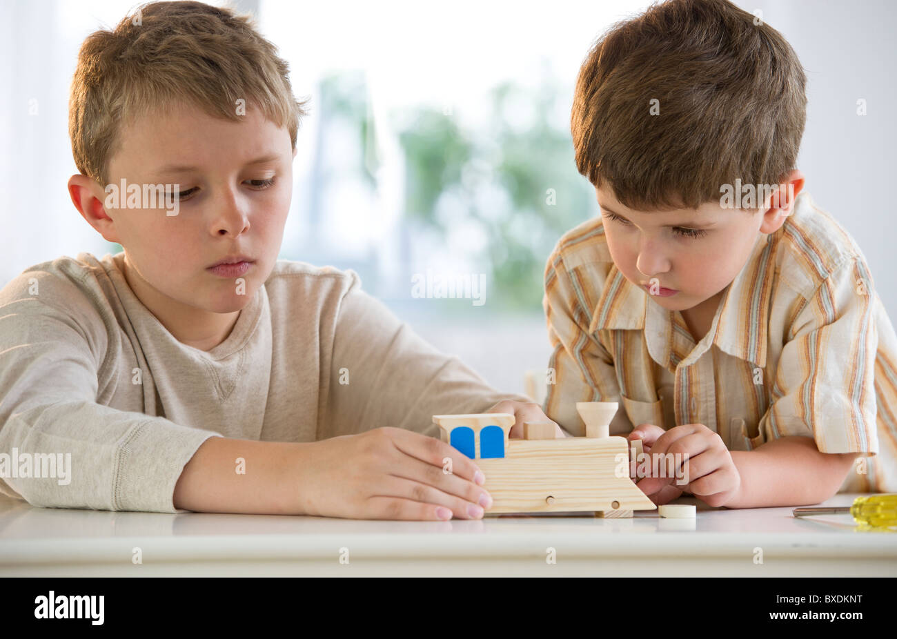 Two young boys building a wooden train Stock Photo