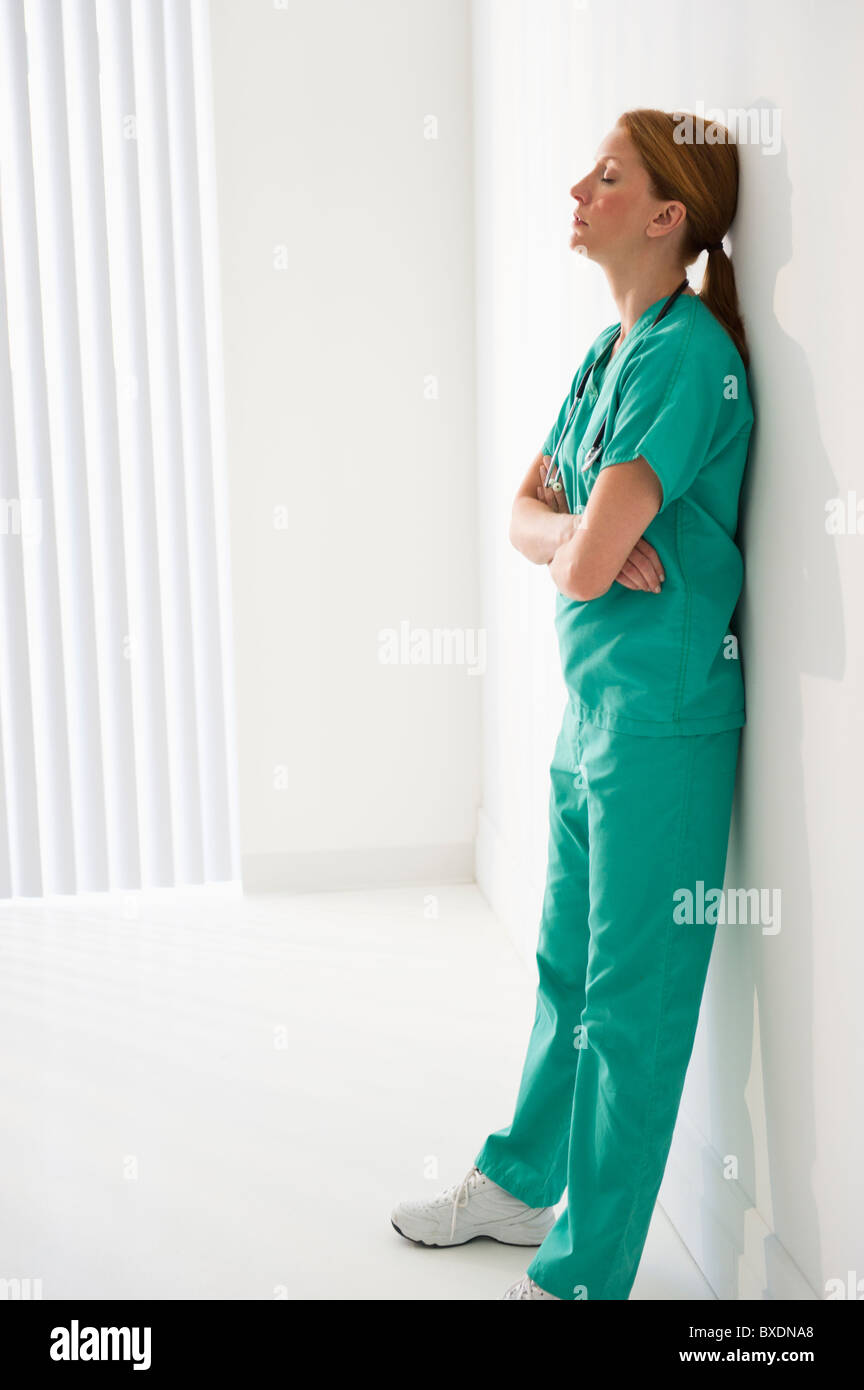 Tired healthcare worker leaning against wall Stock Photo Alamy