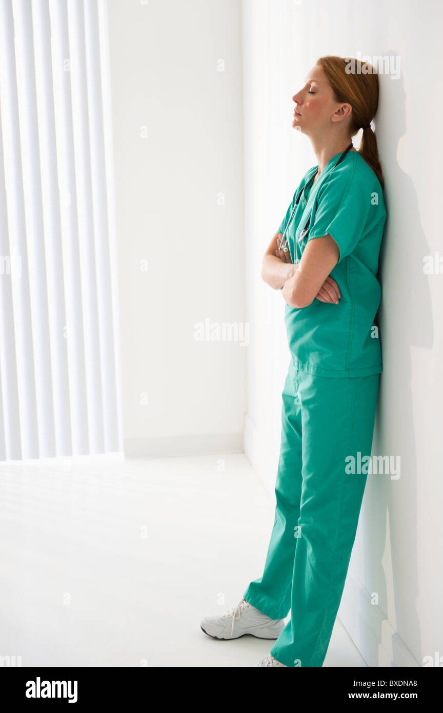 Tired healthcare worker leaning against wall Stock Photo