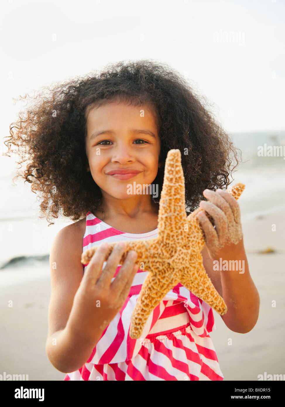 Mixed race girl holding starfish on beach Stock Photo Alamy