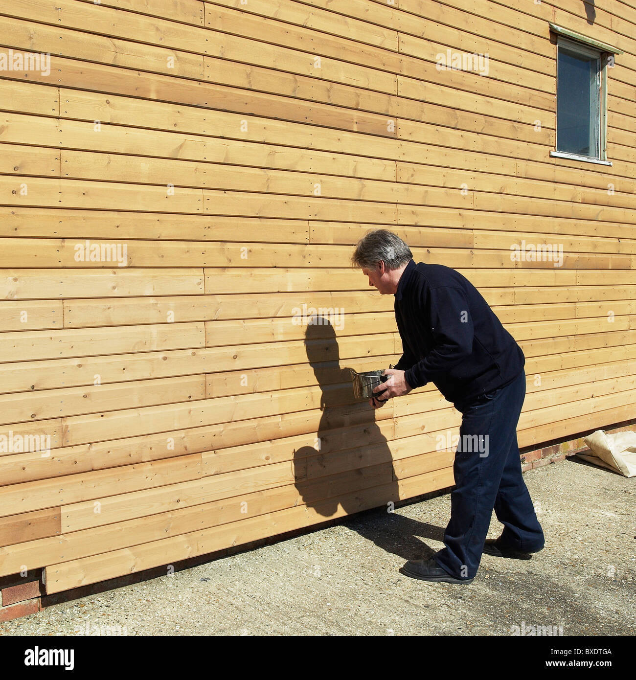 Wood staining weatherboarding on the side of a building Stock Photo