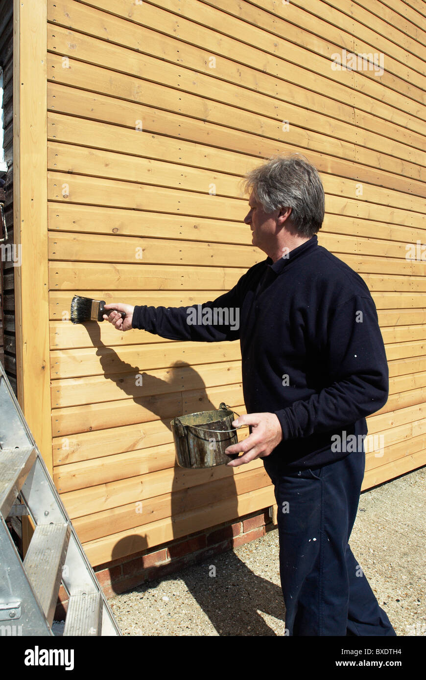 Wood staining weatherboarding on the side of a building Stock Photo