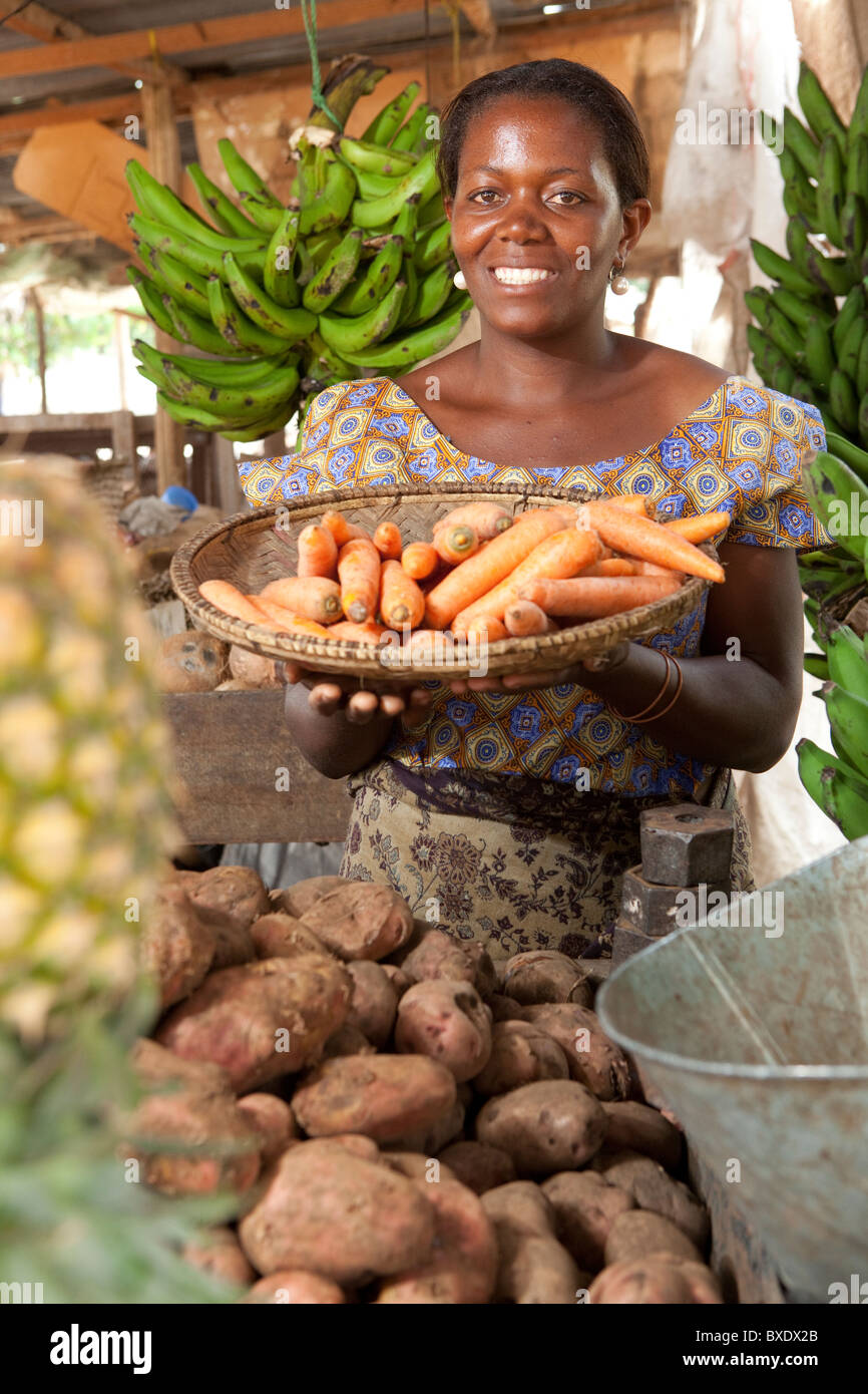 A woman holds a basket of fresh vegetables in the market in Dodoma, Tanzania, East Africa. Stock Photo