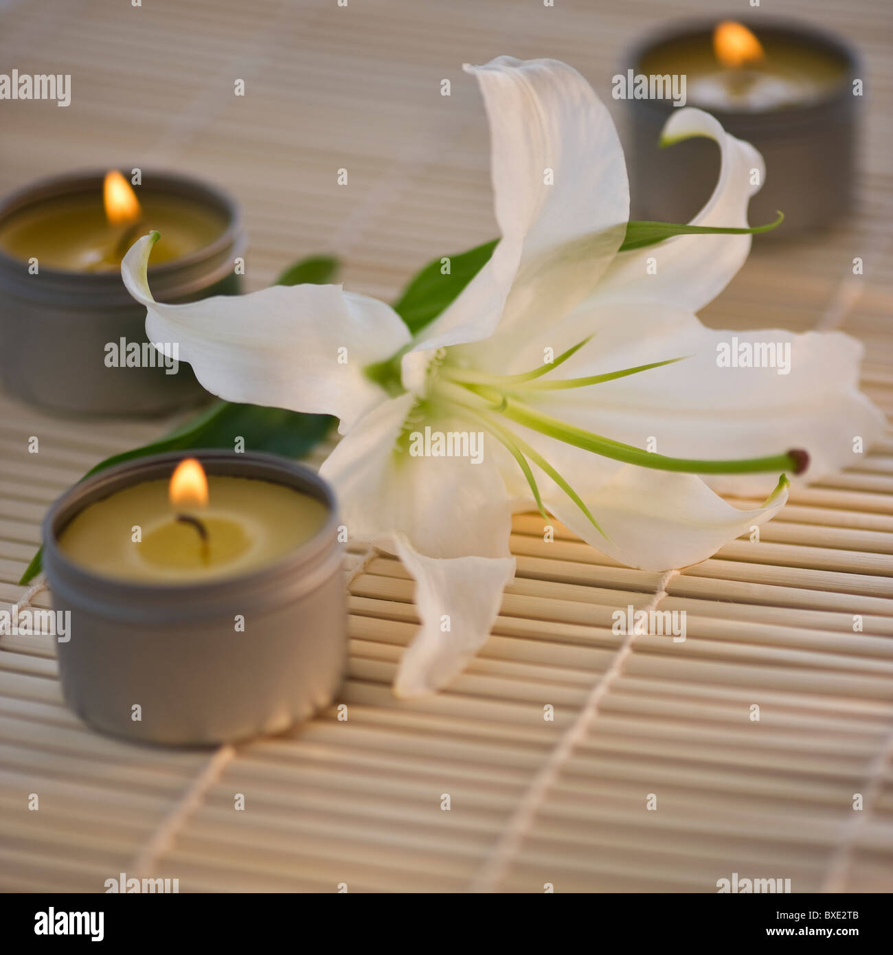 Tea lights and white lily on bamboo mat Stock Photo